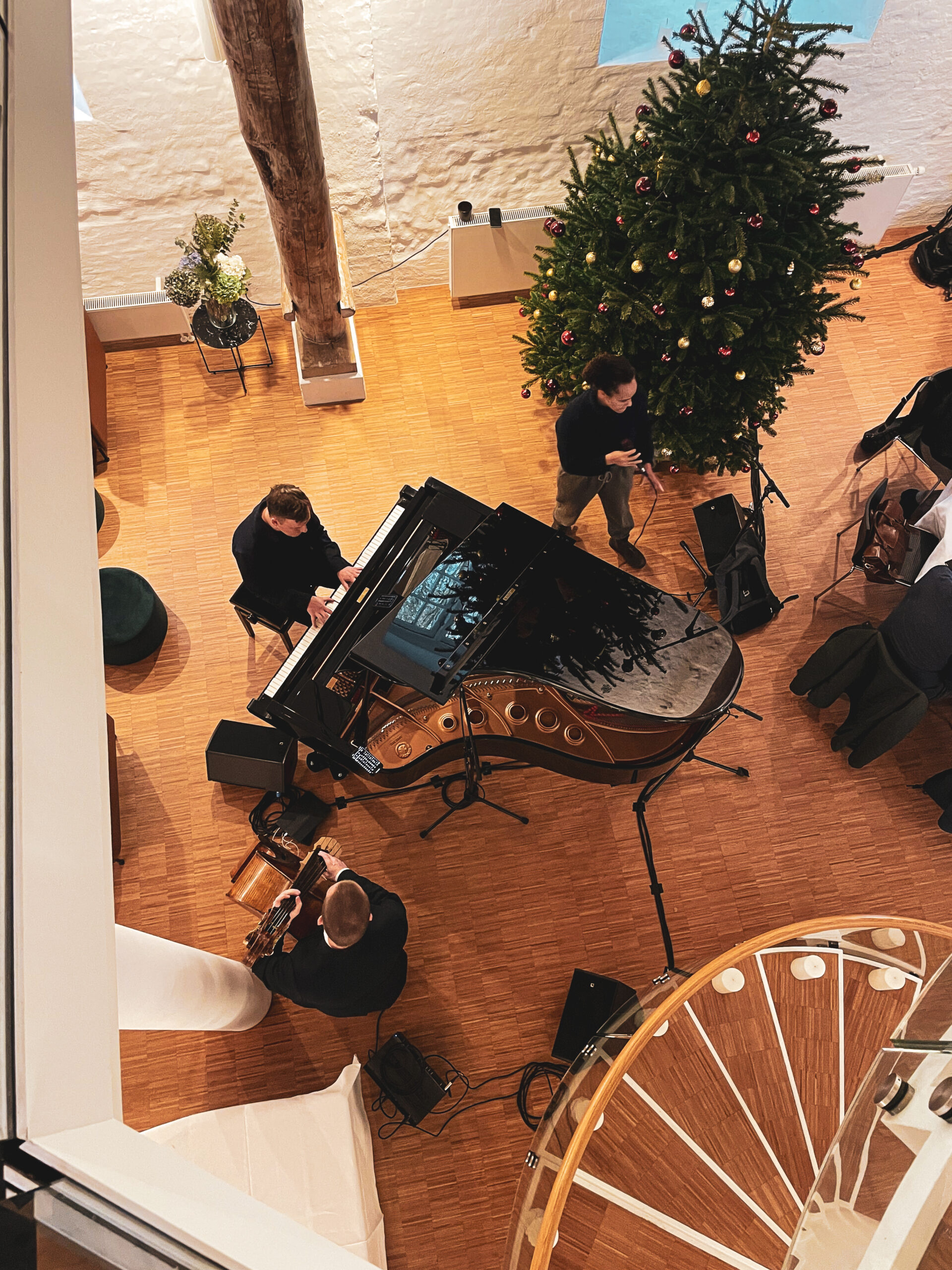 Ein weihnachtlich geschmückter Raum ist der Rahmen für ein Trio, in dem der Pianist spielt und die Sängerin dazu singt.