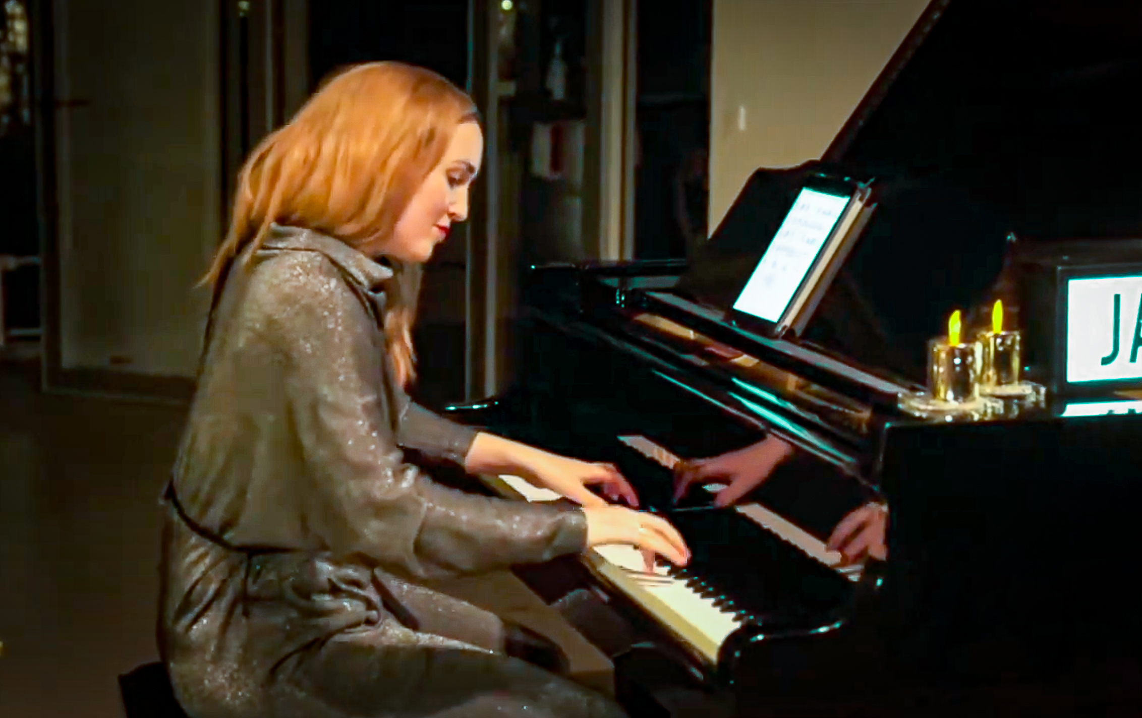 Der Pianist spielt am Flügel, wo Kerzen und Notenblätter eine intime Atmosphäre für das Konzert schaffen.