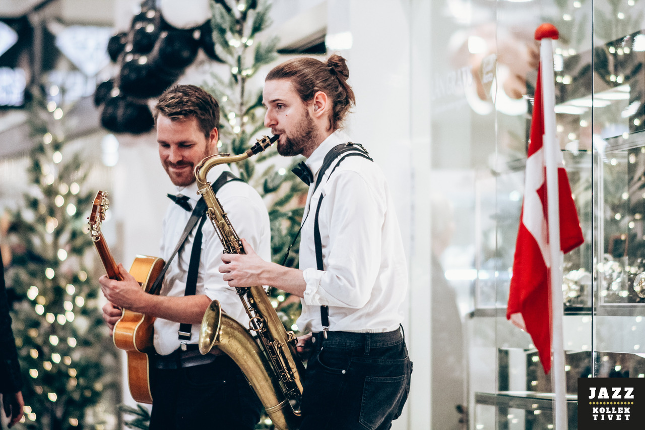Liveband med saxofon og guitar optræder til fest, hvor musikere og gæster skaber en energisk og autentisk stemning i sociale rammer