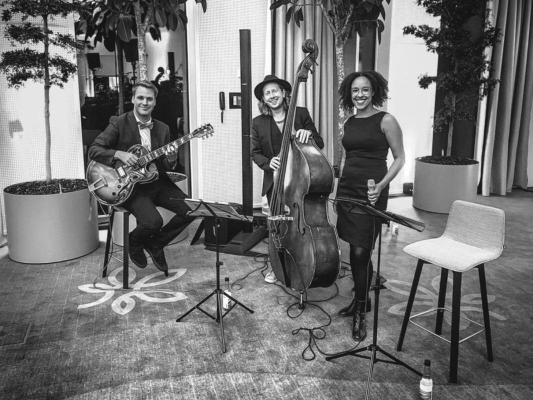 Sort-hvid billede af musikere samlet omkring instrumenter under øvelse, hvilket fremhæver koncentration, samarbejde og tidløs musiktradition